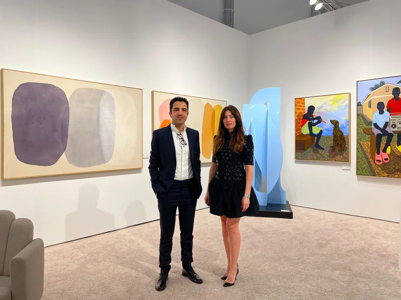 Curator on a fair stand with paintings and sculpture
