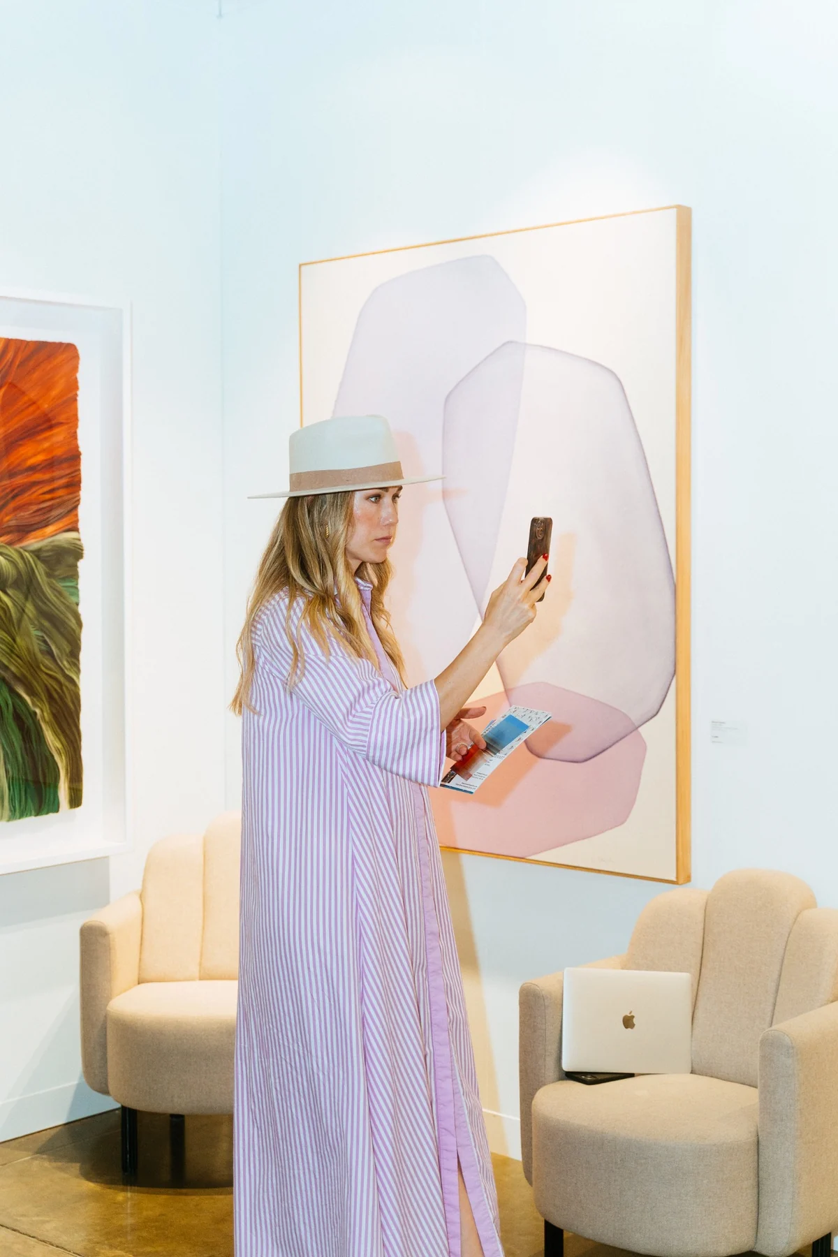 Visitor photographing a painting at an art fair stand